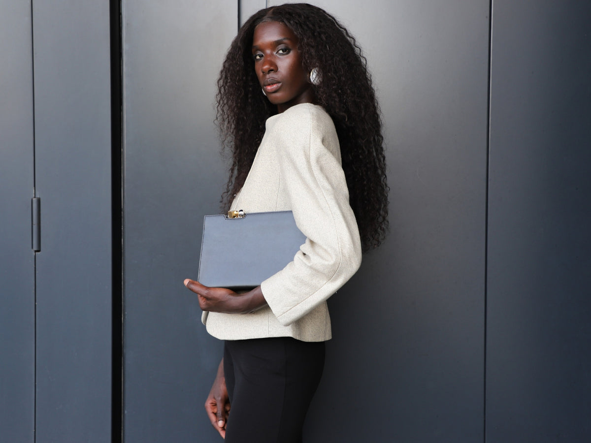 Fashion model wearing minimalist outfit holding Jacquemus clutch bag