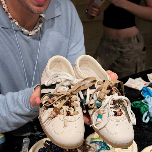 Collanine Colorate team member showing a customer a pair of customized Adidas Samba sneakers during the 2026 Eraldo sneaker customization workshop.