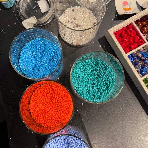 Containers filled with colorful beads arranged on the Collanine Colorate workshop table during the 2026 Eraldo sneaker customization event.