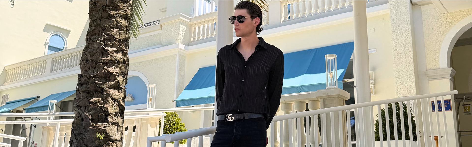 Men's Fall Winter 2026 new arrivals featuring a black Gucci total look with a sheer shirt, side-stripe jeans and GG logo belt.