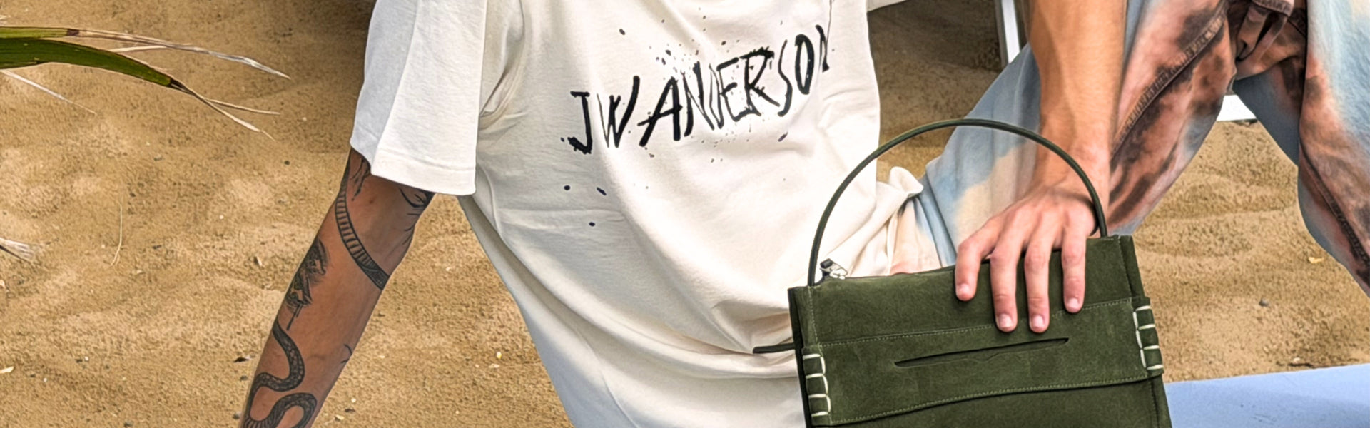 Men's Fall Winter 2026 new arrivals featuring a JW Anderson total look with logo T-shirt, tie-dye effect trousers and green suede bag