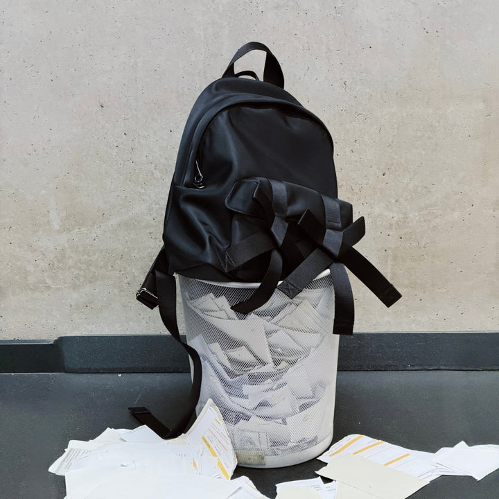 Women's Fall Winter 2026 new arrivals featuring a Simone Rocha black backpack with bow and pearl embellishments, placed on a basket filled with paper.