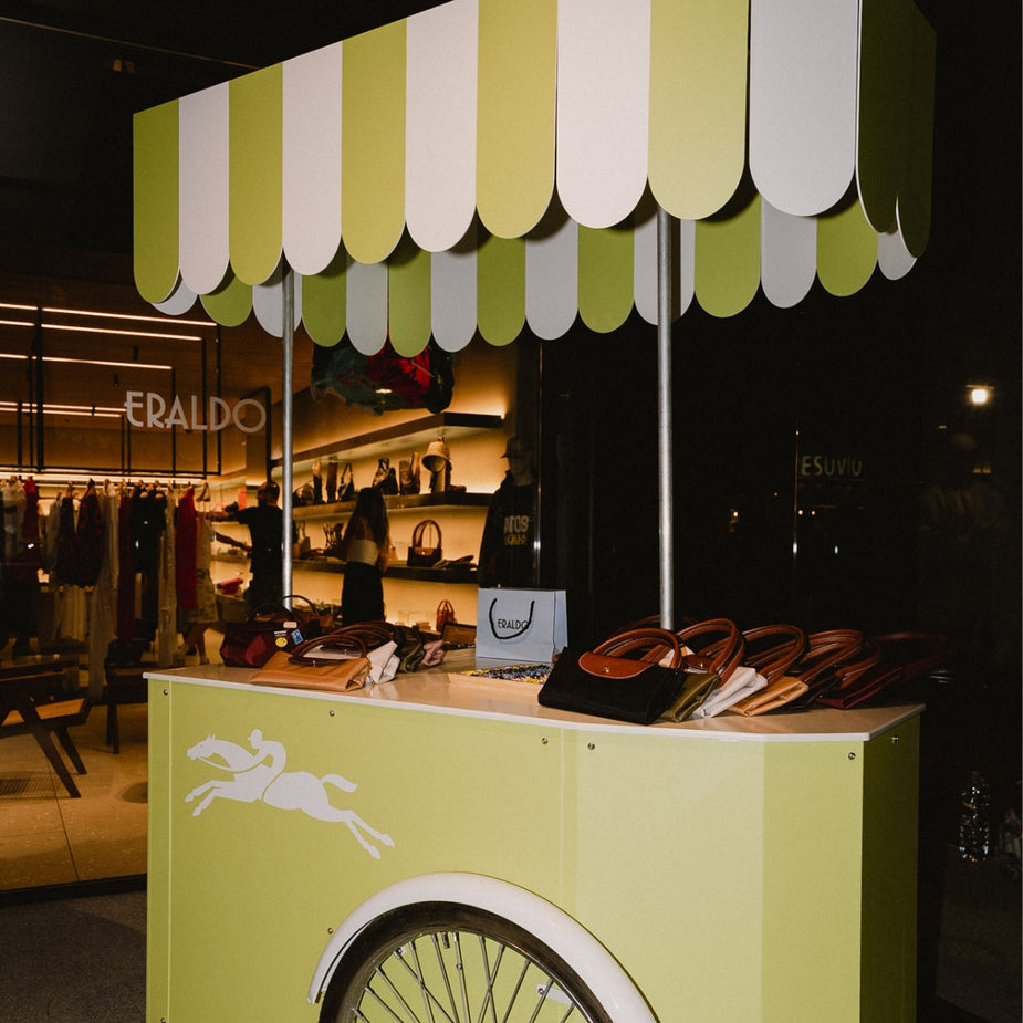 Branded Longchamp customization cart displaying Le Pliage bags and collectible pins for customers to personalize during the AW26 event at Eraldo Store Jesolo.