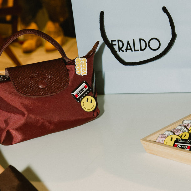Bordeaux mini Longchamp Le Pliage bag personalized with decorative pins displayed next to an Eraldo shopping bag.