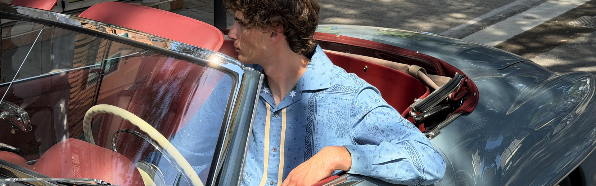 Man sitting on a vintage car wearing a light blue embroidered shirt by Baziszt from the mens shirts selection