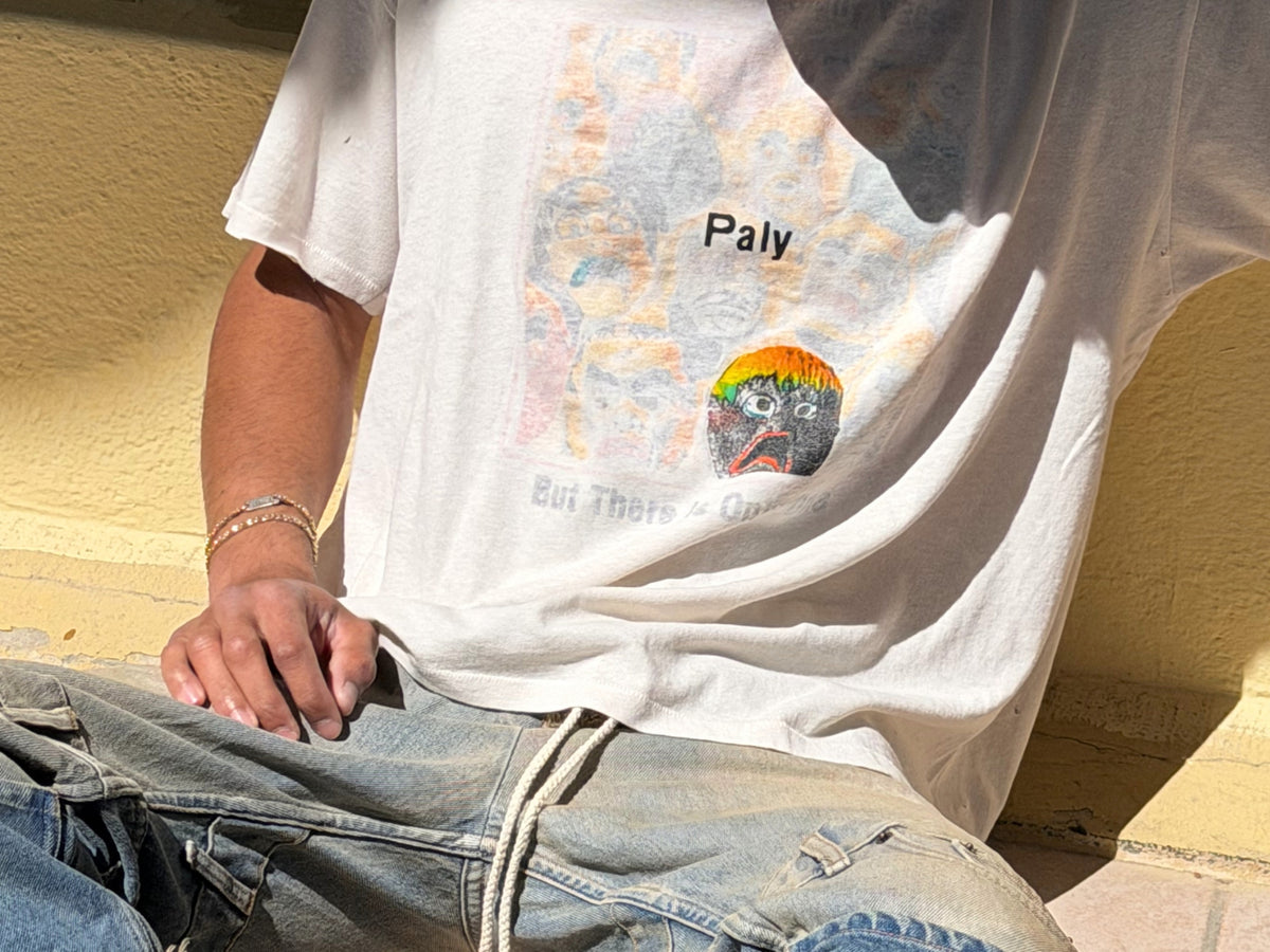 Man wearing a white graphic tank top by PalyHollywood with colorful print