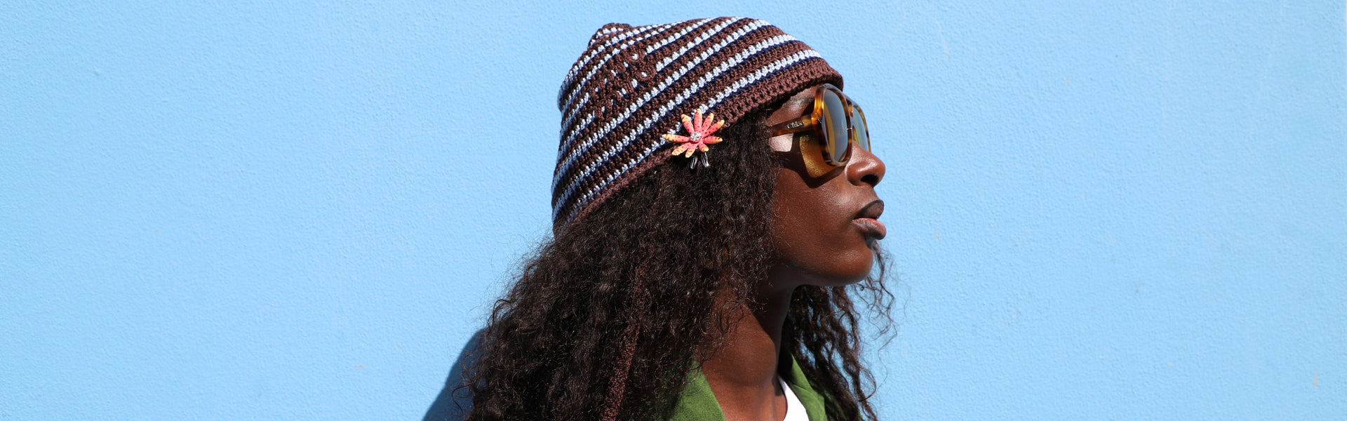 Woman wearing a blue and brown striped cotton hat by Miu Miu and brown tortoiseshell sunglasses by Chloé from the Spring Summer accessories selection