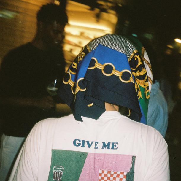 Woman seen from behind wearing a headscarf and an exclusive printed The Attico Vista Mare 2024 event T-shirt.